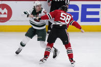 Minnesota Wild center Connor Dewar, left, and Chicago Blackhawks right wing MacKenzie Entwistle fight during the first period of an NHL hockey game in Chicago, Friday, Jan. 21, 2022. (AP Photo/Nam Y. Huh)