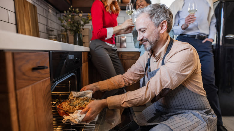 person putting dish in oven