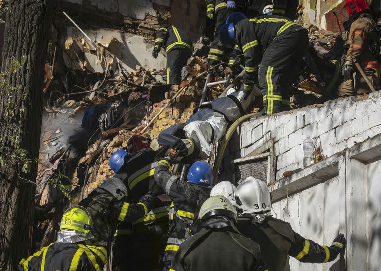 Bomberos sacan un cadáver de entre los escombros tras el ataque de un dron contra edificios residenciales en Kiev, Ucrania, el 17 de octubre de 2022. (AP Foto/Yevhenii Zavhorodnii)