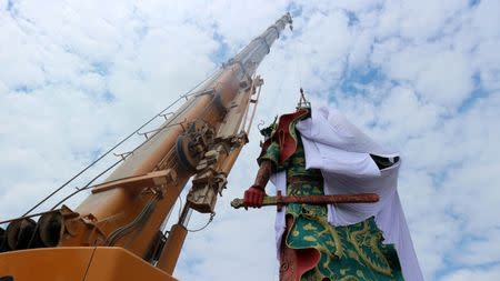 A crane is used to cover the statue of Guan Yu, a Chinese deity, with a cloth in Tuban, about 100 km (60 miles) west of Indonesia's second-biggest city of Surabaya, East Java, Indonesia August 6, 2017 in this photo taken by Antara Foto. Antara Foto/Aguk Sudarmojo/ via REUTERS