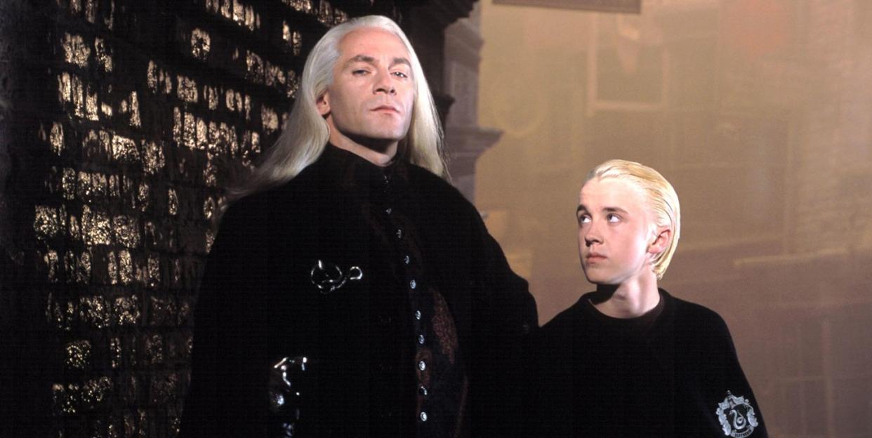 jason isaacs as lucius malfoy standing beside tom felton as draco malfoy, harry potter and the chamber of secrets