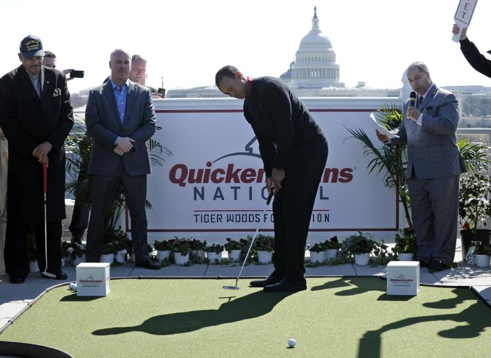 Tiger Woods, center, putts during a putting challenge at the Newseum in Washington, Monday, March 24, 2014. Woods and Quicken Loans Chief Executive Officer Bill Emerson, second from left, participated in the putting challenge to have the mortgage payments paid for three military families for one month. Earlier, Woods and Emerson announced that Quicken Loans had signed a multi-year agreement to become the title sponsor of the Quicken Loans National to be played at Congressional Country Club in Bethesda, Md., in June. (AP Photo/Susan Walsh)