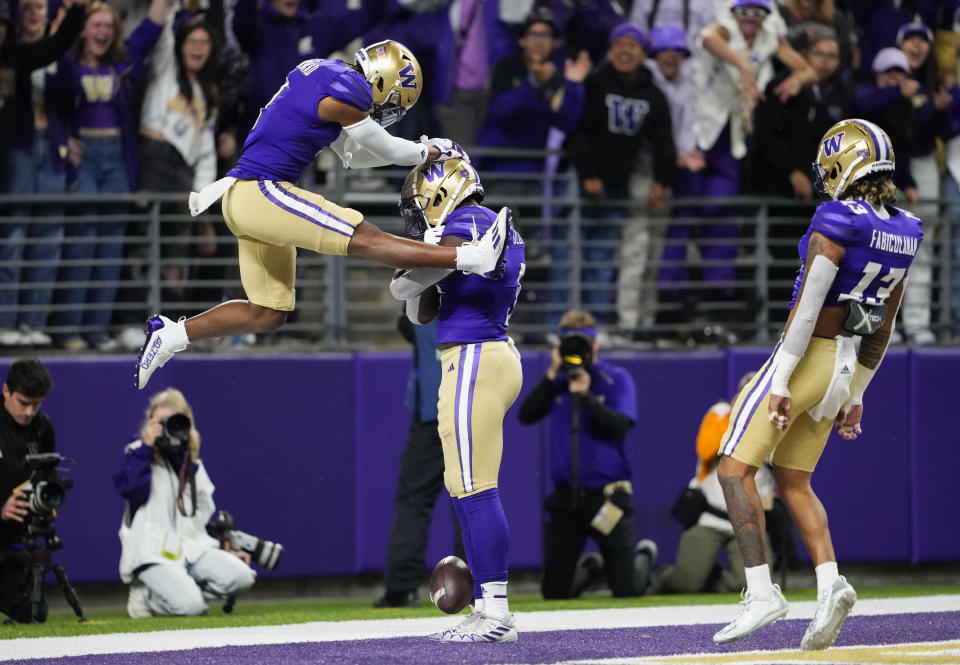 Washington cornerback Jabbar Muhammad, left, jumps up to celebrate after linebacker Edefuan Ulofoshio, center, returned an interception of a California pass for a touchdown, as cornerback Kamren Fabiculanan (13) watches during the first half of an NCAA college football game Saturday, Sept. 23, 2023, in Seattle. (AP Photo/Lindsey Wasson)