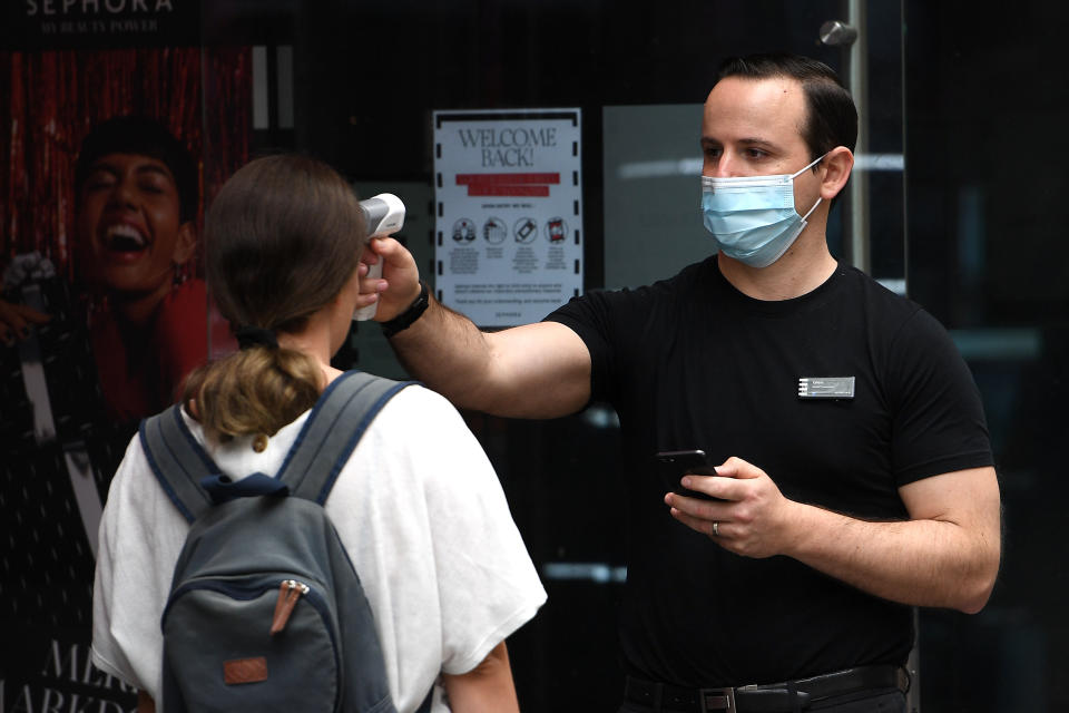 Shoppers are seen being temperature checked on entry to a store in Sydney.