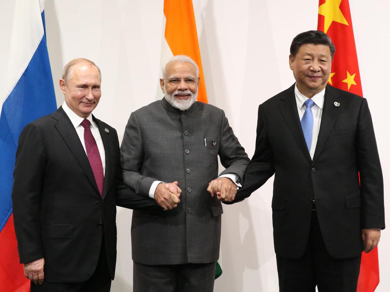 The leaders of India, Russia, and China holding hands and smiling