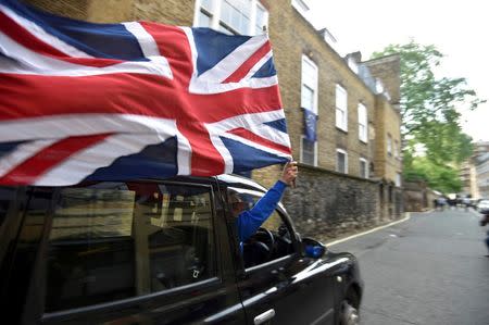 A taxi driver holds a Union flag, as he celebrates following the result of the EU referendum, in central London, Britain June 24, 2016. REUTERS/Toby Melville