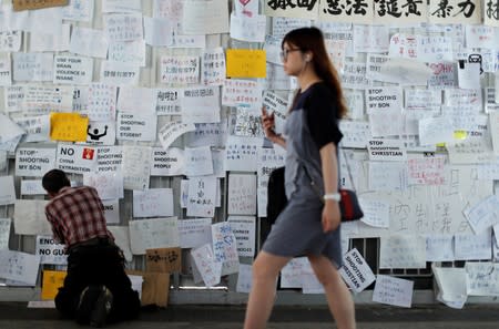 A man sticks notes on the wall near the Legislative Council building, as people gather to wait for a government announcement regarding the proposed extradition bill, in Hong Kong