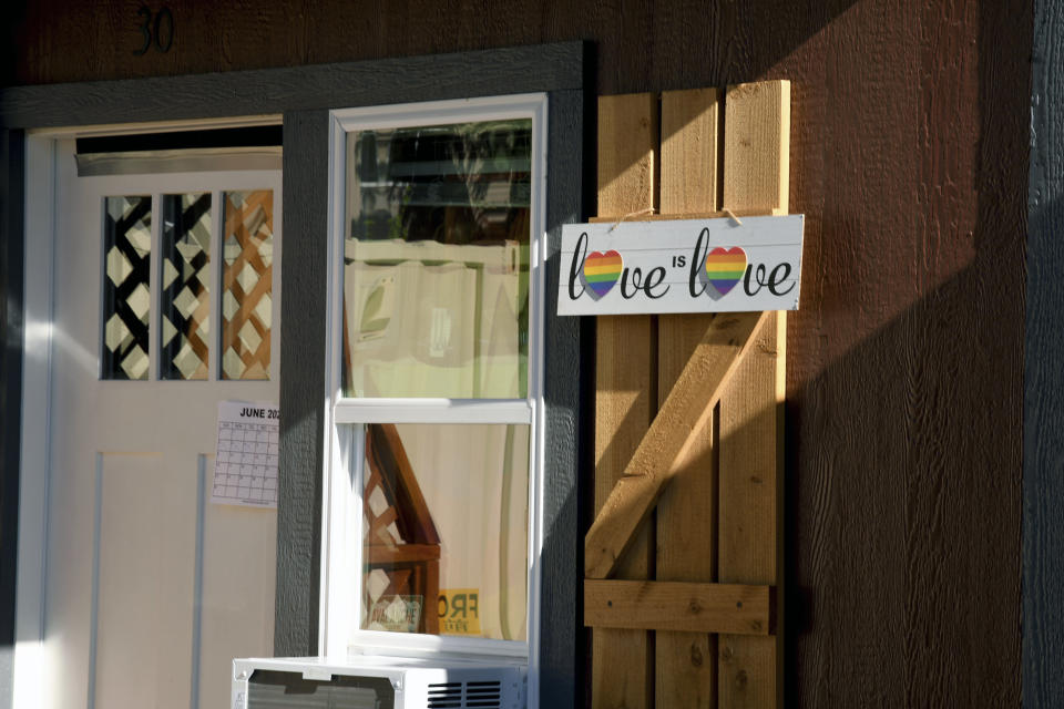A Love is Love sign is displayed at a micro community in Denver on Wednesday, June 5, 2024. The communities consist of small cabin-like structures with a twin bed, desk and closet. The city built three such communities with nearly 160 units total in about six months, at roughly $25,000 per unit to ease homelessness. (AP Photo/Thomas Peipert)
