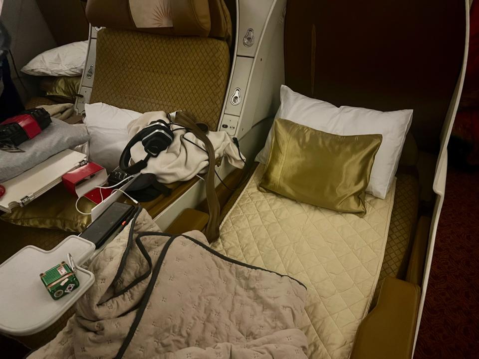 The bed in lie-flat mode with the gold and white linens and mattress pad.