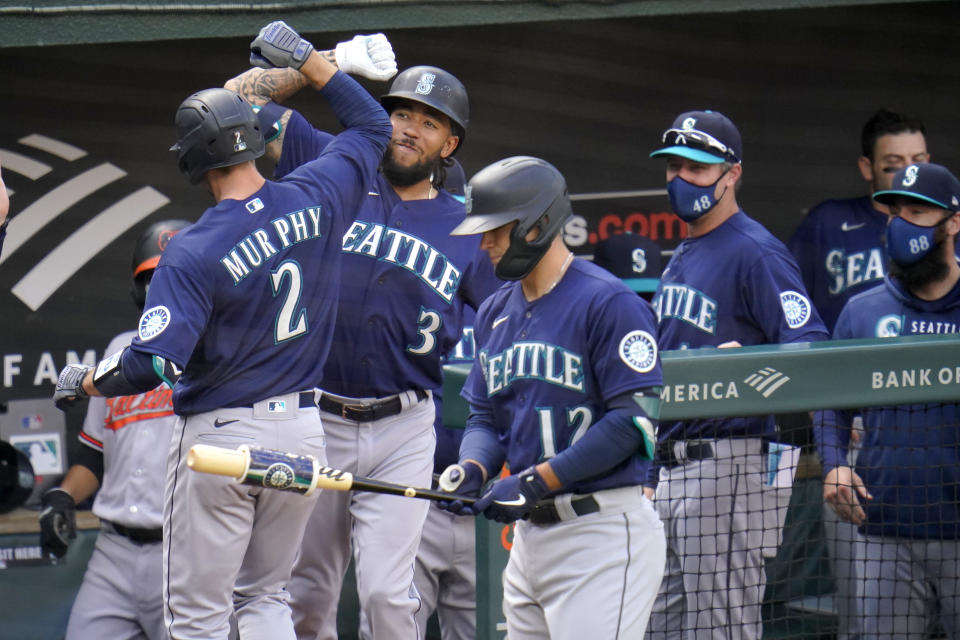 Seattle Mariners' Tom Murphy (2) is greeted near the dugout by J.P. Crawford (3) after hitting a solo home run off Baltimore Orioles starting pitcher John Means during the second inning of the first game of a baseball doubleheader, Tuesday, April 13, 2021, in Baltimore. (AP Photo/Julio Cortez)