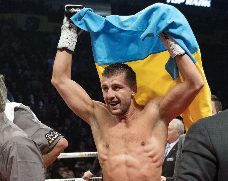 Oleksandr Gvozdyk raises the Ukrainian flag to celebrate his win over Adonis Stevenson, of Canada, and winning the light heavyweight WBC championship boxing fight, Saturday, Dec. 1, 2018, in Quebec City. (Jacques Boissinot/The Canadian Press via AP)