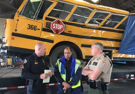 Christopher Hart (C), chairman of the National Transportation Safety Board, speaks with Chattanooga Police and Tennessee Highway Patrol officers while viewing the wreck of a school bus in which several children were killed, at a depot in Chattanooga, Tennessee, U.S. November 22, 2016. NTSB/Handout via REUTERS