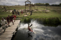 A man wearing a Roman soldier outfit is thrown into a river during a battle at the Romula Fest historic reenactment festival in the village of Resca, Romania, Sunday, Sept. 4, 2022. (AP Photo/Andreea Alexandru)