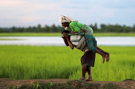 A Rohingya refugee man carries an elderly woman after crossing the border in Palang Khali, Bangladesh, October 9, 2017. REUTERS/Mohammad Ponir Hossain