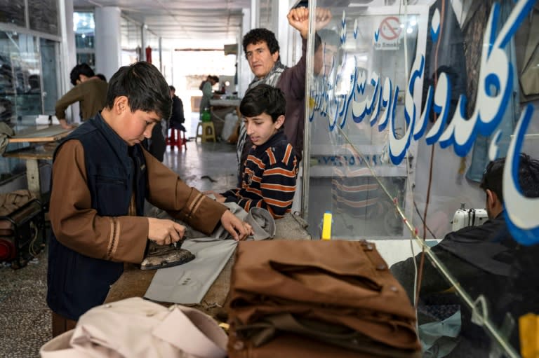 Un jeune Afghan (g) repasse des vêtements avant l'Aïd al-Fitr, qui marque la fin du mois de jeûne du ramadan, dans un atelier de couture, le 7 avril 2024 à Kaboul (Wakil KOHSAR)