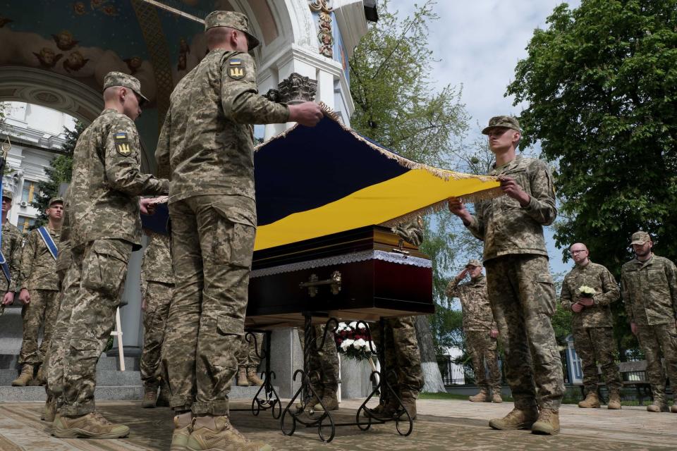 Ukrainian soldiers hold a flag about the coffin of Christopher Campbell at the farewell ceremony of the U.S. volunteer in Kyiv on May 5, 2023. (Francis Farrell/The Kyiv Independent)