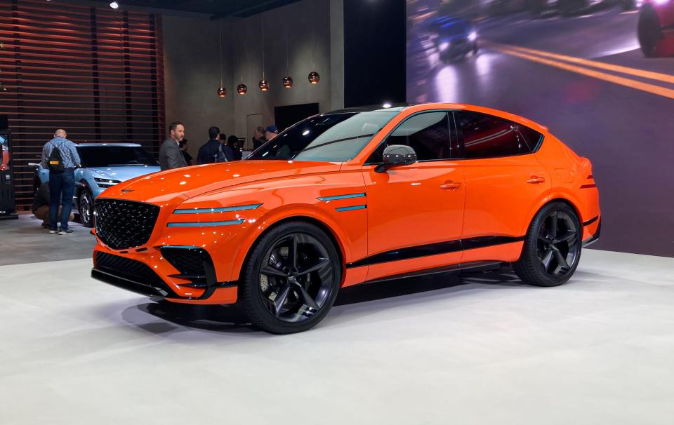 An orange Genesis GV80 Coupe Concept SUV on a white floor.