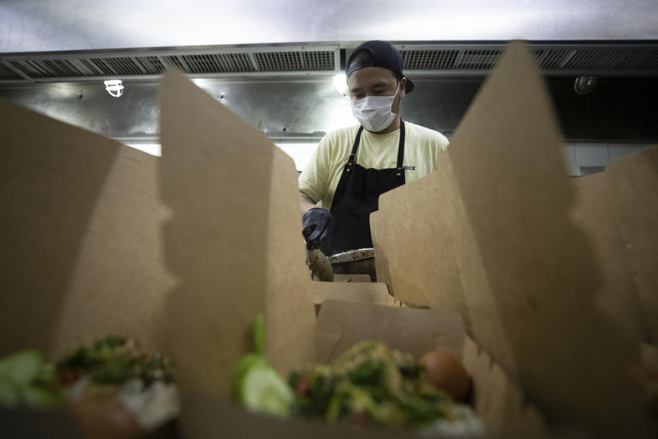 Volunteer of COVID Thailand Aid, chef Napol Jantraget from Thailand fills "pad krapow gai", the spicy minced chicken in a box for the railway-side community at Bo.lan restaurant in Bangkok, Thailand Wednesday, June 10, 2020. Thailand's Natalie Bin Narkprasert, who runs a business in Paris, was stranded in her homeland by a flight ban, so she decided to use her skills to organize a network of volunteers, including Michelin-starred chefs, to help those in her homeland whose incomes were most affected by the pandemic restrictions. (AP Photo/Sakchai Lalit)