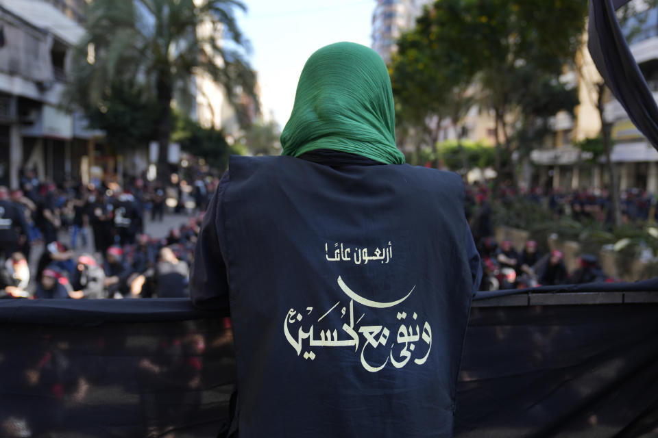 A Hezbollah member wears a vest with Arabic that reads: "40 years and we stay with Hussein (the Prophet Muhammad's grand son)," during the holy day of Ashoura that commemorates the 7th century martyrdom of the Prophet Muhammad's grandson Hussein, in the southern suburb of Beirut, Lebanon, Aug. 9, 2022. Forty years since it was founded, Lebanon's Hezbollah has transformed from a ragtag organization to the largest and most heavily armed militant group in the Middle East. (AP Photo/Hussein Malla)