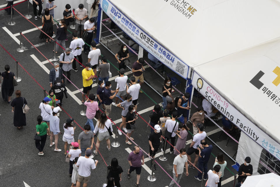 People queue in line to wait to get coronavirus testing at a Public Health Center in Seoul, South Korea, Sunday, July 11, 2021. The banner reads: "Quick scan with QR Code." (AP Photo/Ahn Young-joon)