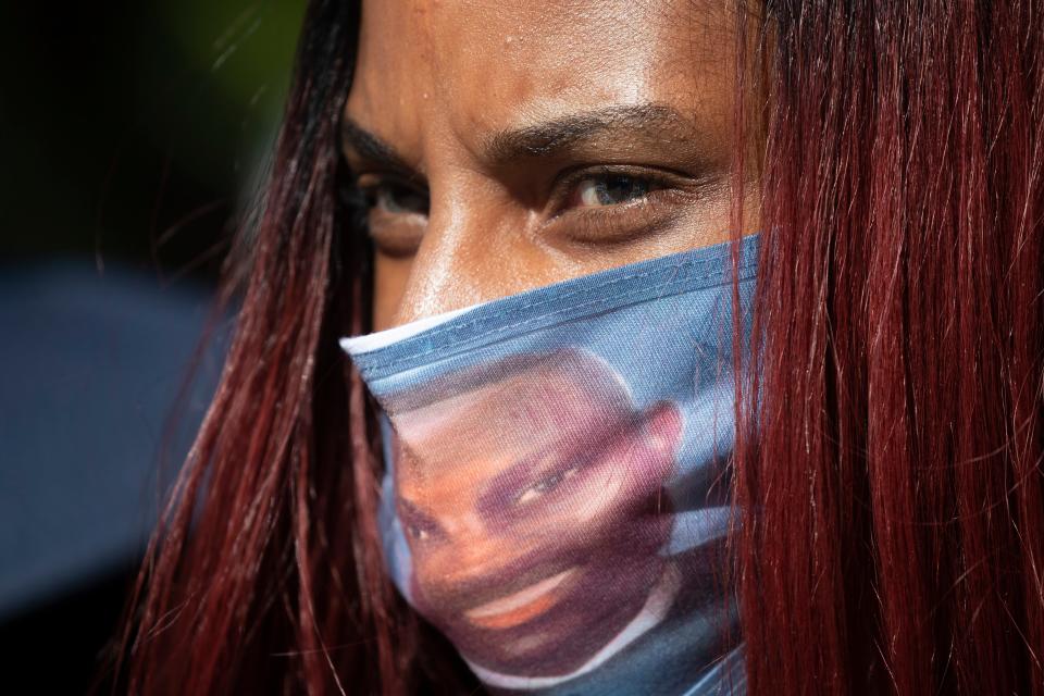 A woman wears a face covering with the likeness of shooting victim Ahmaud Arbery printed on it during a rally to protest Arbery's killing Friday, May 8, 2020, in Brunswick Ga.