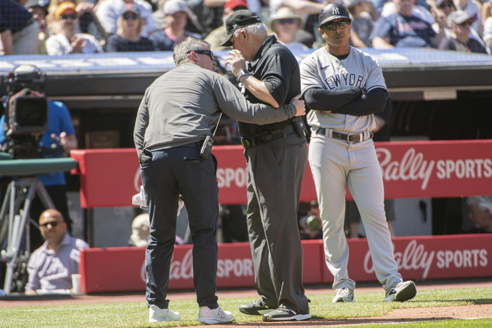 Umpire Larry Vanover is attended to by a Cleveland Guardians trainer after being hit by a throw from the outfield during the fifth inning of a baseball game in Cleveland, Wednesday April 12, 2023. Vanover left the game because of the injury. Vanover remained hospitalized Thursday after being hit in the head with the relay throw Wednesday. (AP Photo/Phil Long)