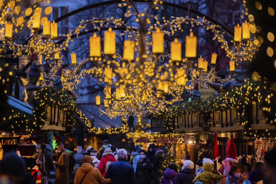 Visitors walk through the Christmas market at Alter Markt, Cologne, Germany, Monday, Nov. 29, 2021. Chancellor Angela Merkel will hold talks Tuesday with the governors of Germany's 16 states amid growing concern about the steep rise in new coronavirus cases in the country. (Rolf Vennenbernd/dpa via AP)