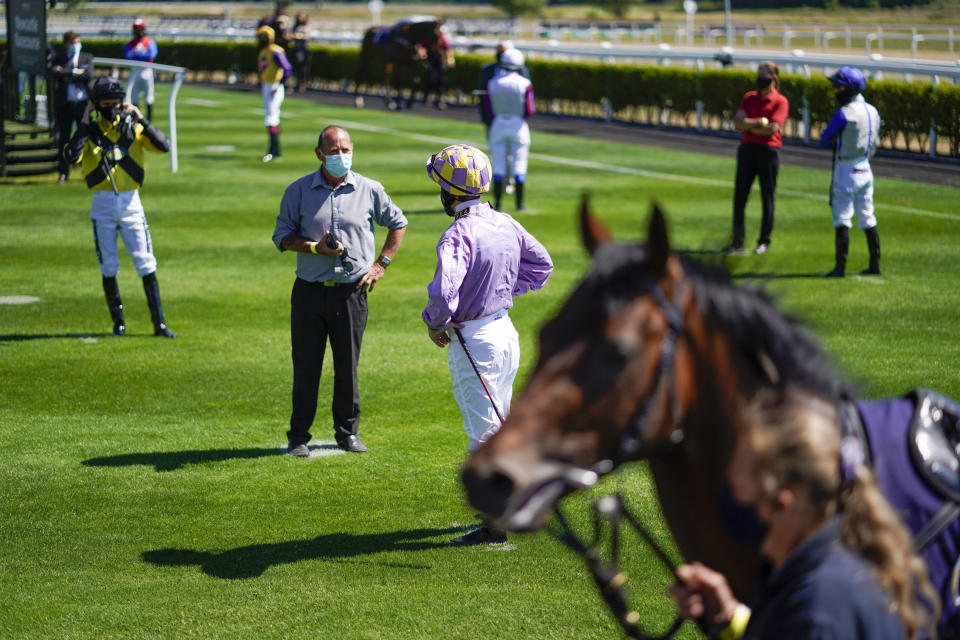 Jockeys observe social distancing as they stand in the paddock before a race as horse racing is resumed at Newcastle Racecourse, in Newcastle, England, Monday June 1, 2020. Horse Racing in the UK returned to action on Monday, but resuming without spectator racegoers following the coronavirus shutdown. (Alan Crowhurst / PA via AP)