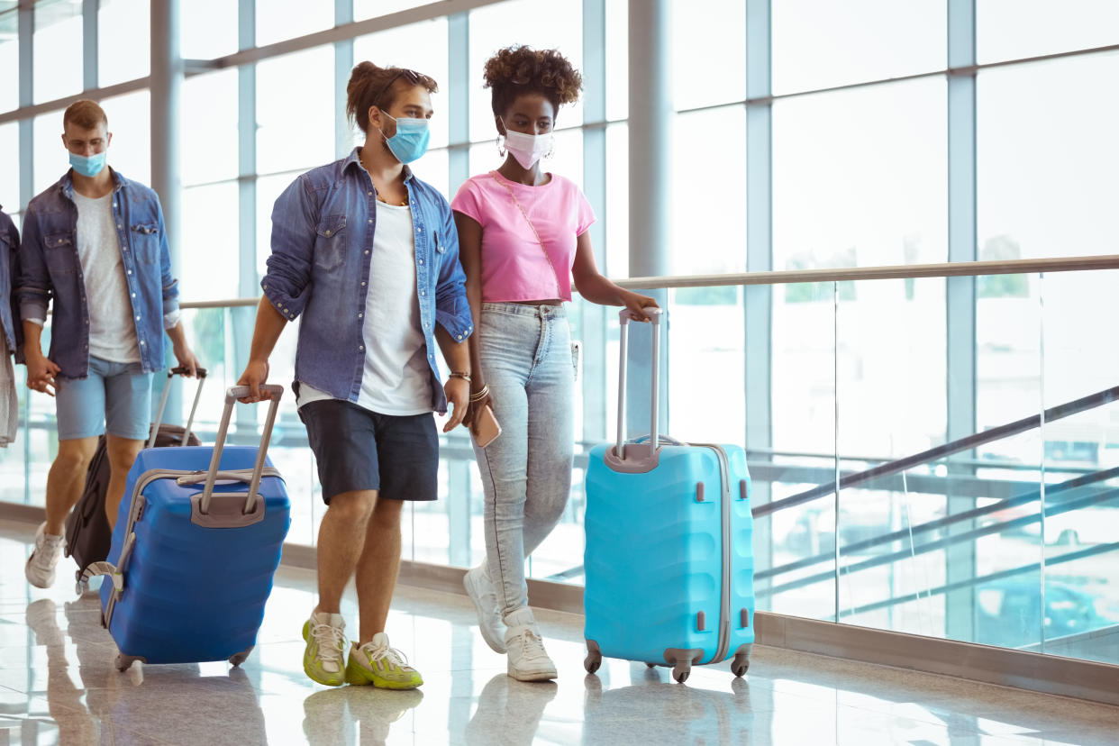 Young people traveling by plane, carrying luggage in airport terminal.