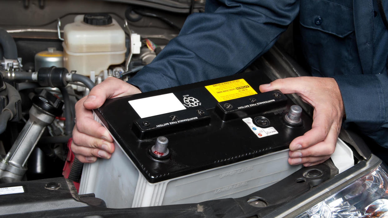 A car mechanic replaces a battery.