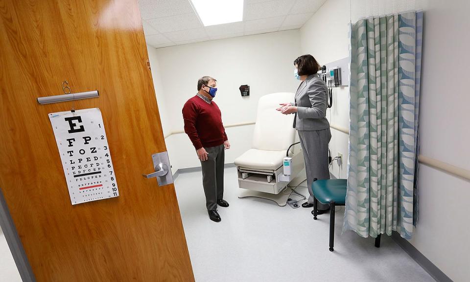 Mayor Thomas Koch looks at an exam room area at the Manet Community Health Center in Houghs Neck, Quincy, with CEO Cynthia Sierra on Thursday, Dec. 3, 2020.