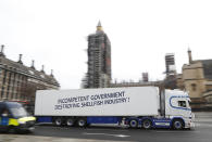 A shellfish export truck with a protest sign written across the trailer 'Incompetent Government Destroying Shellfish Industry" drives past the Palace of Westminster in London, Monday, Jan. 18, 2021, during a demonstration by British Shellfish exporters to protest Brexit-related red tape they claim is suffocating their business. (AP Photo/Alastair Grant)