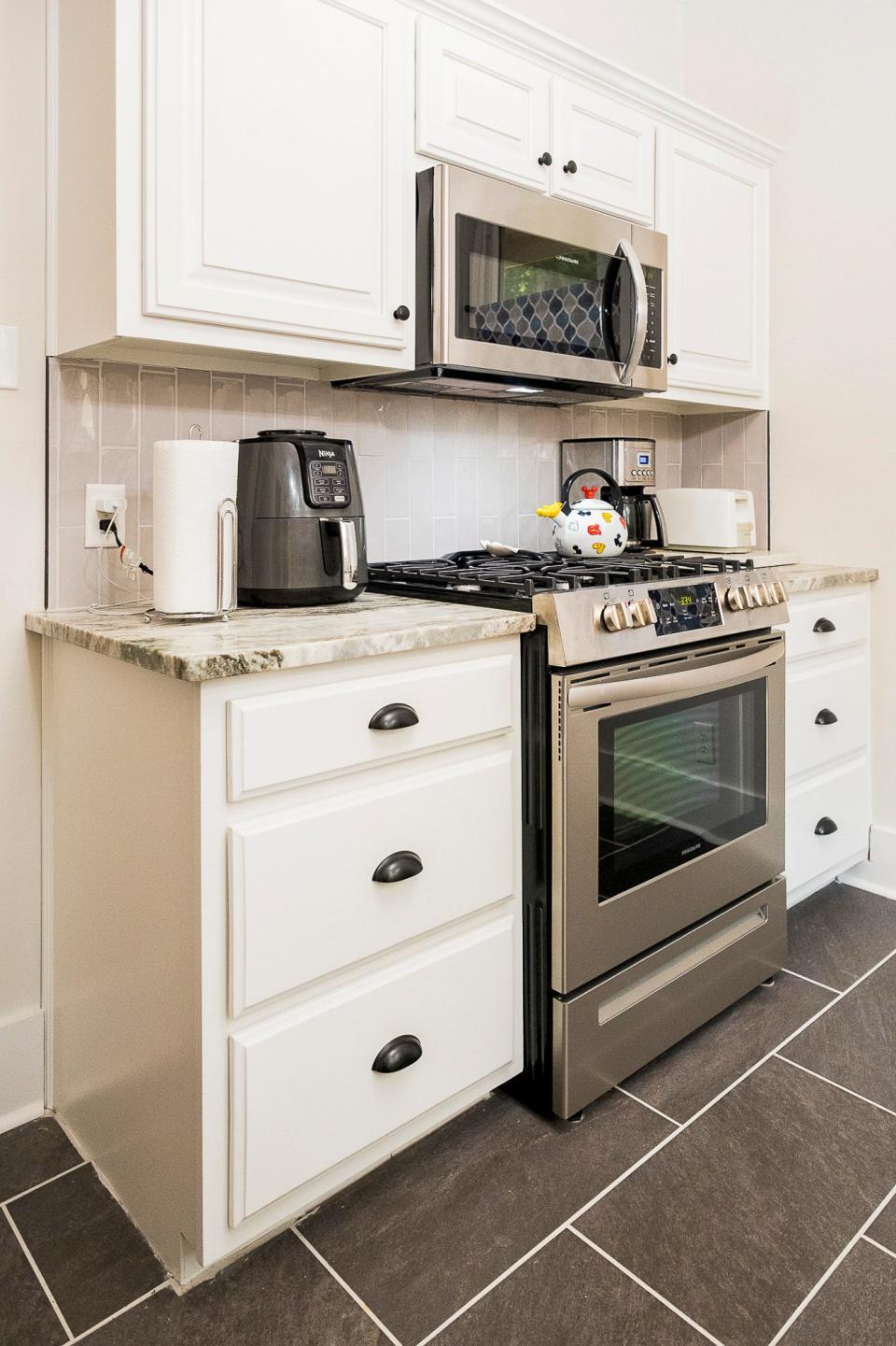 This modern kitchen appears to be new from top to bottom; however, the original cabinetry was kept in place and repainted white. The addition of new countertops, along with new flooring and modern appliances, was completed by a previous owner.