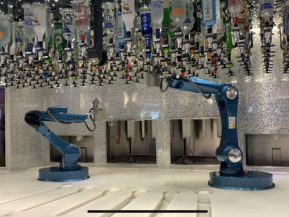 machines making cocktails underneath alcohol bottles