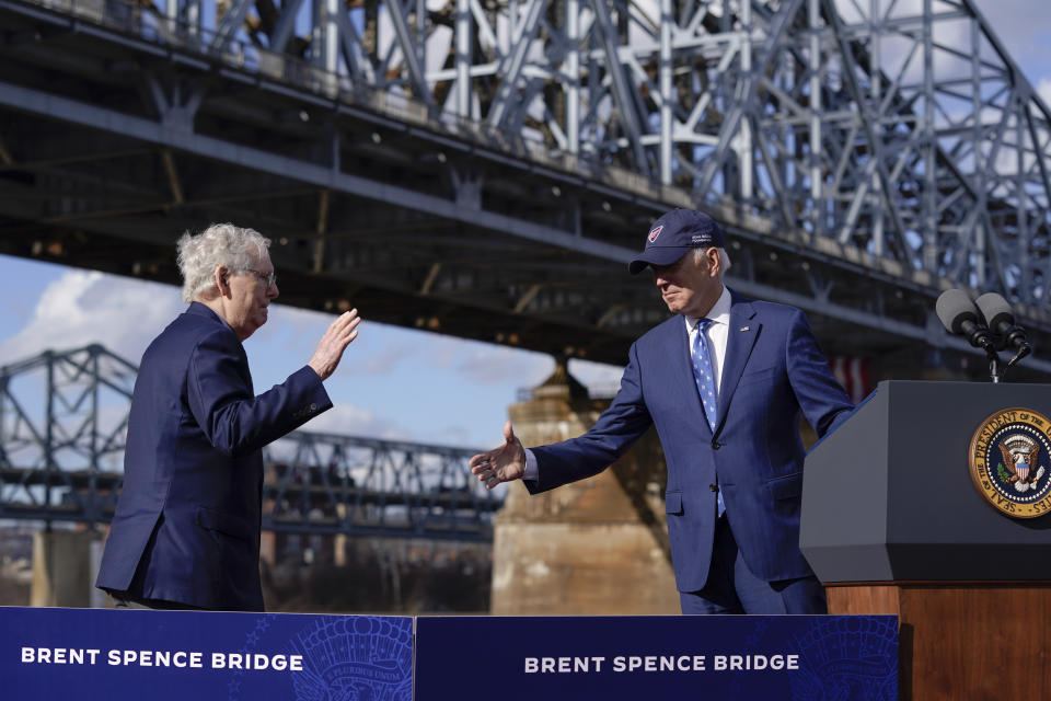 President Joe Biden and Senate Minority Leader Mitch McConnell of Ky., reach out to shake hands after Biden spoke about his infrastructure agenda under the Clay Wade Bailey Bridge, Wednesday, Jan. 4, 2023, in Covington, Ky. Biden's infrastructure deal that was enacted in late 2021 will offer federal grants to Ohio and Kentucky to build a companion bridge that is intended to alleviate traffic on the Brent Spence Bridge, background at left. (AP Photo/Patrick Semansky)