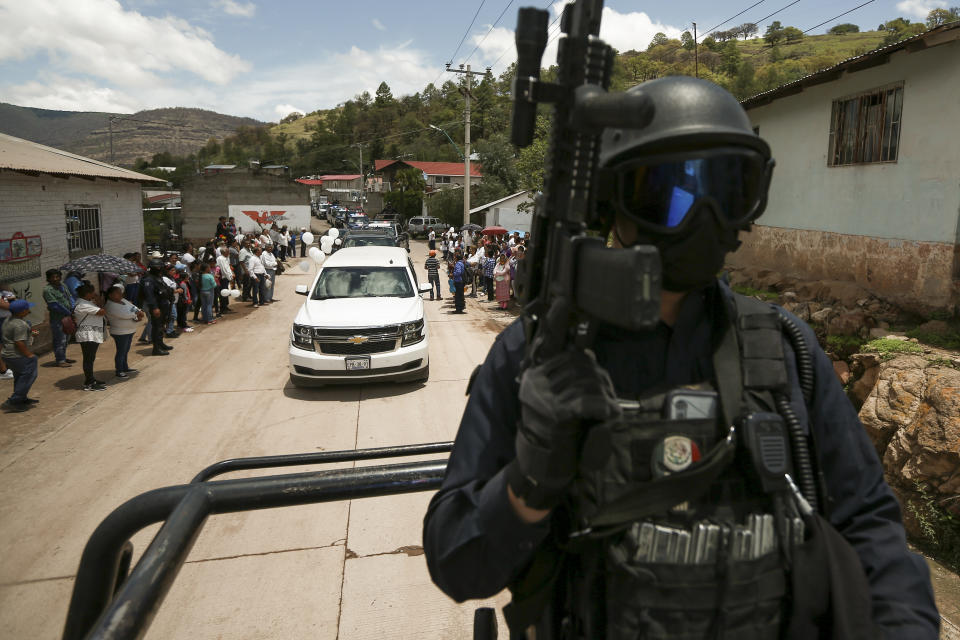 A policeman escorts the funeral procession of Jesuit priests Javier Campos Morales and Joaquin Cesar Mora Salazar arrive to Cerocahui, Chihuahua state, Mexico, Sunday, June 26, 2022. The two elderly priests and a tour guide murdered in Mexico's Sierra Tarahumara this week are the latest in a long line of activists, reporters, travelers and local residents who have been threatened or killed by criminal gangs that dominate the region. (AP Photo/Christian Chavez)