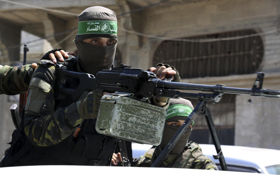 A masked militant from the Izzedine al-Qassam Brigades, a military wing of Hamas, stands behind a machine gun on a truck as mourners carry the body of Osama Dueij, 32, who was shot in the leg on Saturday during a violent demonstration on the northern border between Gaza and Israel, during his funeral procession in Jebaliya refugee camp, northern Gaza Strip, Wednesday, Aug. 25, 2021. (AP Photo/Adel Hana)