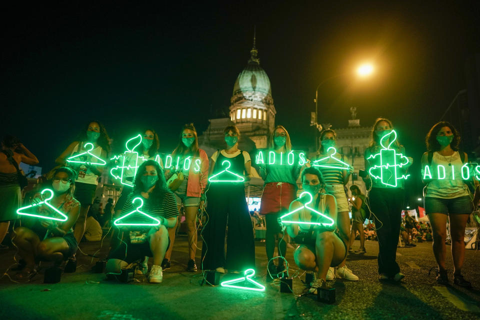 FILE - In this Dec. 30, 2020 file photo, abortion-rights activists hold hangers, that symbolize illegal abortions, and signs reading in Spanish "Goodbye" after lawmakers approved a bill that legalizes abortion, outside Congress in Buenos Aires, Argentina. (AP Photo/Victor Caivano, File)