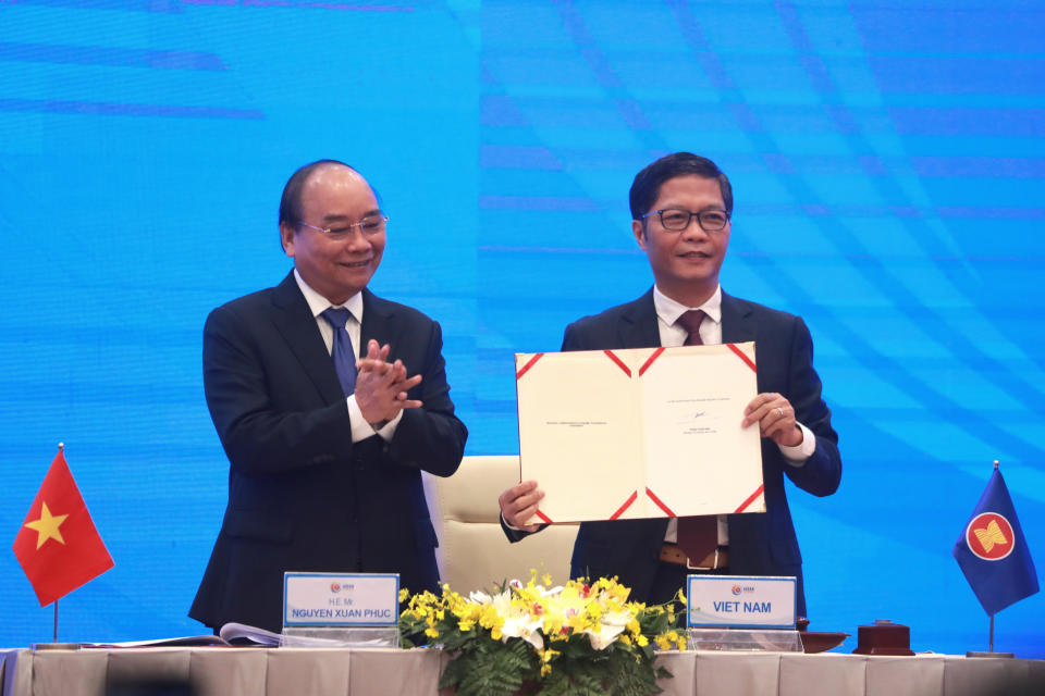 Vietnamese Prime Minister Nguyen Xuan Phuc, left, applauds as Minister of Trade Tran Tuan Anh, right, holds up a signed document during a virtual signing ceremony of the Regional Comprehensive Economic Partnership, or RCEP, trade agreement in Hanoi, Vietnam on Sunday, Nov. 15, 2020. China and 14 other countries have agreed to set up the world's largest trading bloc, encompassing nearly a third of all economic activity, in a deal many in Asia are hoping will help hasten a recovery from the shocks of the pandemic. (AP Photo/Hau Dinh)