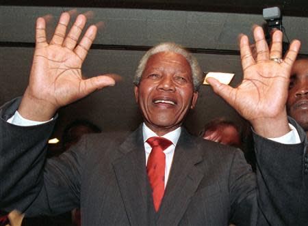 ANC leader Nelson Mandela raises his hands to ask everyone to respect security as he moves through a group of supporters at the Johannesburg Stock exchange, in this April 22, 1994 file photo. REUTERS/Corinne Dufka/Files