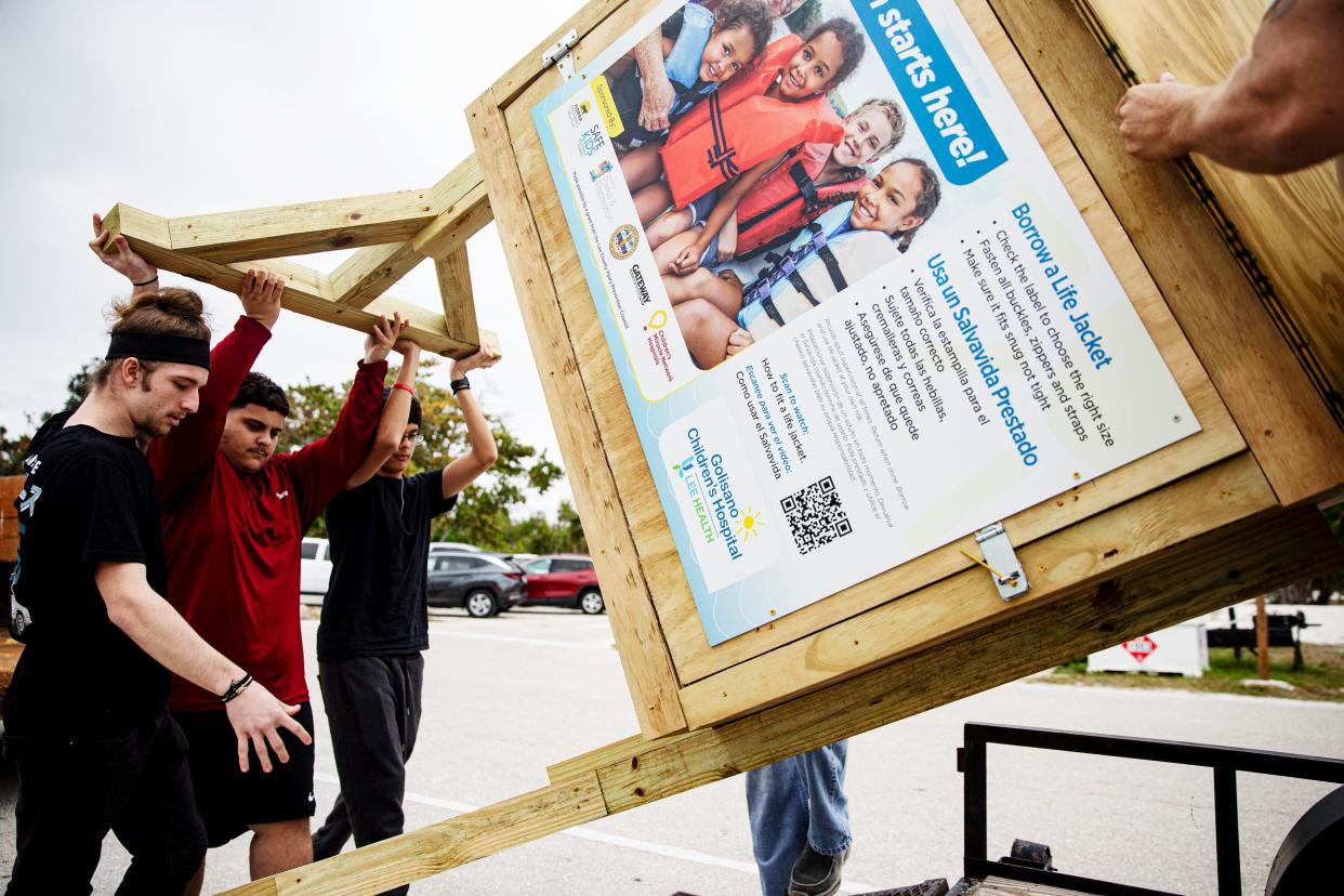 Gateway High School students, from left, Quinton Molnar, Devin Shannon and Christian Champ, help their carpentry teacher, J.T. Schurr drop off a life jacket loaner station at Lovers Key State Park on Thursday, Jan. 4, 2024. The station was built by the students at Gateway High School in partnership with Lee Health and others. Tina Fleming, a injury prevention specialist with Safe Kids Worldwide at Golisano Children's Hospital secured grants to get six stands built. Two are already placed. The stations offer life jackets to those who need them while visiting area beaches. Several Life jacket stands were lost in Hurricane Ian. It also offers the students to practice a trade they may be interested in pursing after high school.