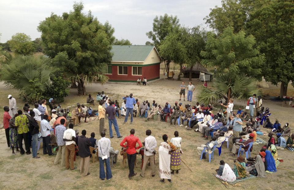 In this photo taken Dec. 17, 2012 and released by the Moran Eye Center, patients from the Dinka, Nuer, & Murle tribes who have just had sight-restoring surgery gather with caregivers and local tribe commissioners for a "Peace Circle" conducted by John Dau, a former "Lost Boy" of Sudan who fled conflict there by walking to Ethiopia and eventually found his way to Syracuse New York, in the village of Duk Payuel in Jonglei state, South Sudan. South Sudan's government faces monumental challenges: To bring warring factions, often from rival ethnic groups, back toward peace after violence broke out across the country on Dec. 15, but a group of American doctors has a unique approach to help heal age-old rifts between the ethnic groups, eye surgery, although it has been put on hold because of the fighting. (AP Photo/Moran Eye Center, Timothy O'Neill)