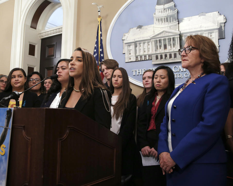 Olympic Gold Medalist Aly Raisman, foreground left, joined by dozens of victims of sexual assault by USC's Dr. George Tyndall, speaks in support of a measure by Assemblywoman Eloise Gomez Reyes, D-,San Bernardino, right, that would extend the statute of limitations to file civil lawsuits against Tyndall, at the Capitol Tuesday, April 23, 2019, in Sacramento, Calif. Tyndall, who was an OB GYN at the USC health center, is accused of sexually assaulting and abusing women under his care for nearly three decades. Raisman was assaulted by former USA Gymnastics doctor Larry Nassar. (AP Photo/Rich Pedroncelli)