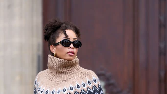 a woman wearing an oversized light brown fair isle sweater with jeans and sunglasses on teh street in pairs in a roundup of the best oversized sweaters 2024