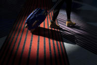 A traveler walks with a suitcase through the terminal at Washington Reagan National Airport, Wednesday, Nov. 21, 2018, in Arlington, Va. The airline industry trade group Airlines for America expects that Wednesday will be the second busiest day of the holiday period behind only Sunday, when many travelers will be returning home after Thanksgiving. (AP Photo/Carolyn Kaster)