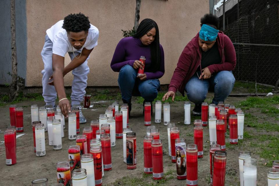 Three people look after a candle memorial.