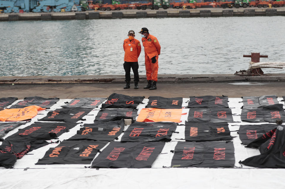 Members of National Search and Rescue Agency (BASARNAS) confer near body bags containing human remains retrieved from from the Java Sea where Sriwijaya Air flight SJ-182 crashed on Saturday, at Tanjung Priok Port in Jakarta, Indonesia, Thursday, Jan. 14, 2021. An aerial search for victims and wreckage of a crashed Indonesian plane expanded Thursday as divers continued combing the debris-littered seabed looking for the cockpit voice recorder from the lost Sriwijaya Air jet. (AP Photo/Dita Alangkara)