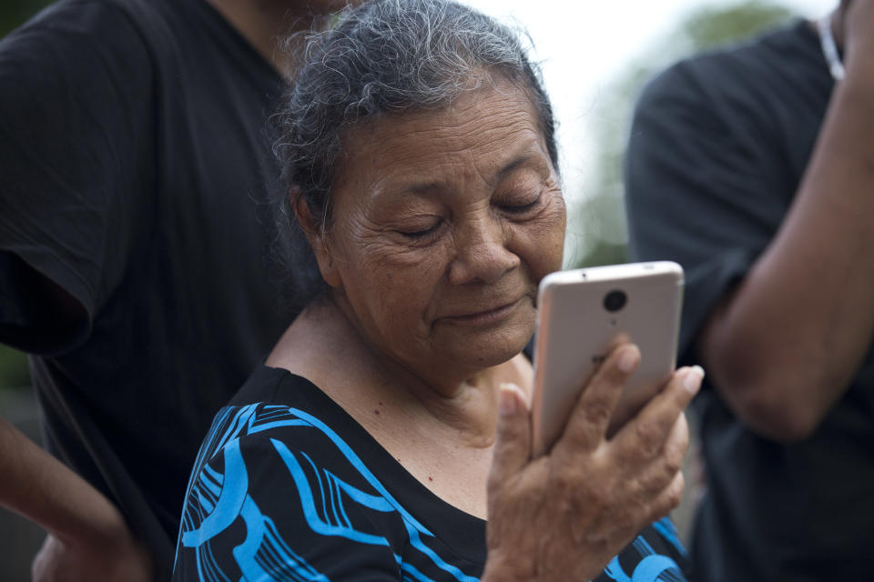 In this Oct. 31, 2018 photo, Haydee Posadas takes a video call from a relative, during the burial of her son Wilmer Gerardo Nunez, at a cemetery in San Pedro Sula, Honduras. Nearly eight years after her son went missing, an Argentine forensics team confirmed he was one of the 72 migrants killed in the 2010 San Fernando ranch massacre. "My heart hurt so much ... most of all because of the death he suffered, not even knowing who killed him, with his eyes blindfolded, hands tied..." Posadas said. (AP Photo/Moises Castillo)