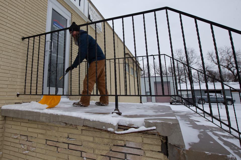 Shawn Holthaus, an employee with A-1 Plumbing, helps to scrape away snow and ice Thursday morning just outside a building at 110 N.E. Lyman Road.
