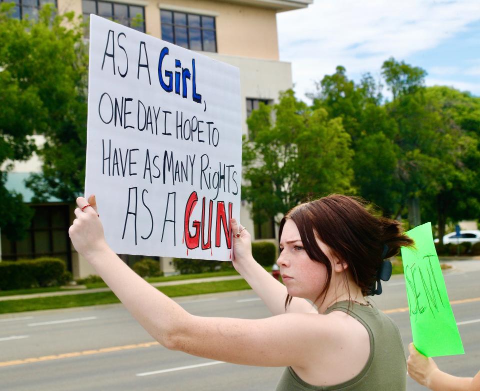 Riley Nemchick of Shasta Lake shows a sign to drivers along Cypress Avenue during a women's rights protest on Monday, July 4, 2022.